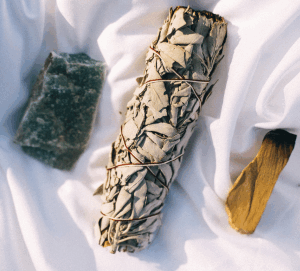 Rough crystal, white sage bundle and palo santo stick.