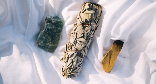 Rough crystal, white sage bundle and palo santo stick.